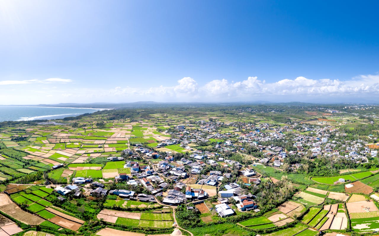 Stunning aerial view of a rural village and farmland under a clear blue sky.