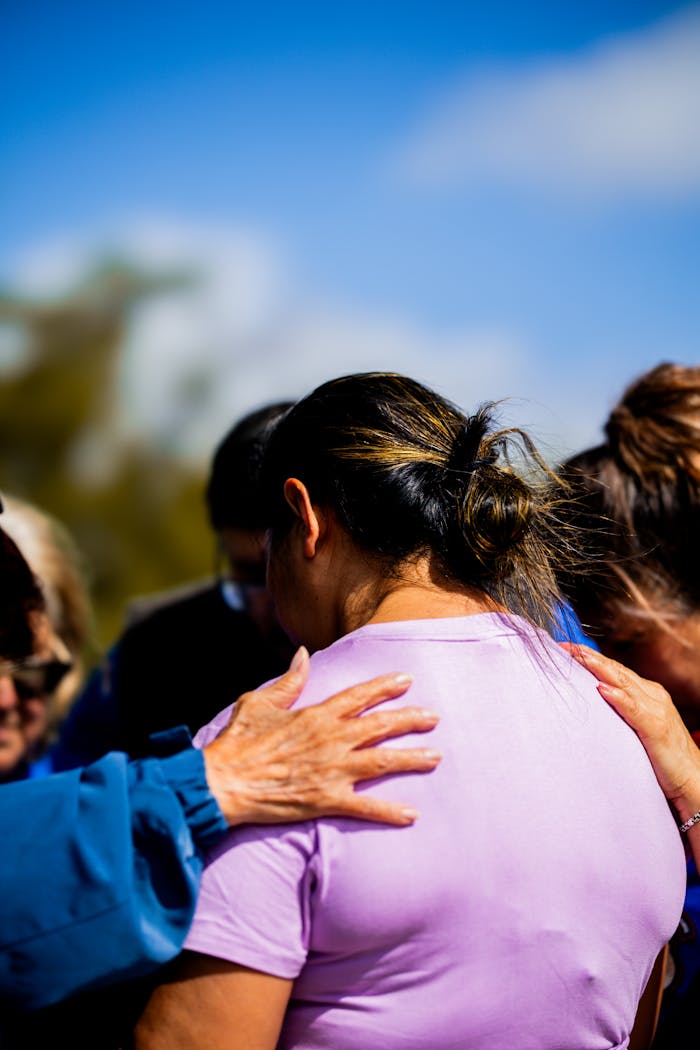 A group of people supporting each other outdoors during the day, emphasizing community and empathy.