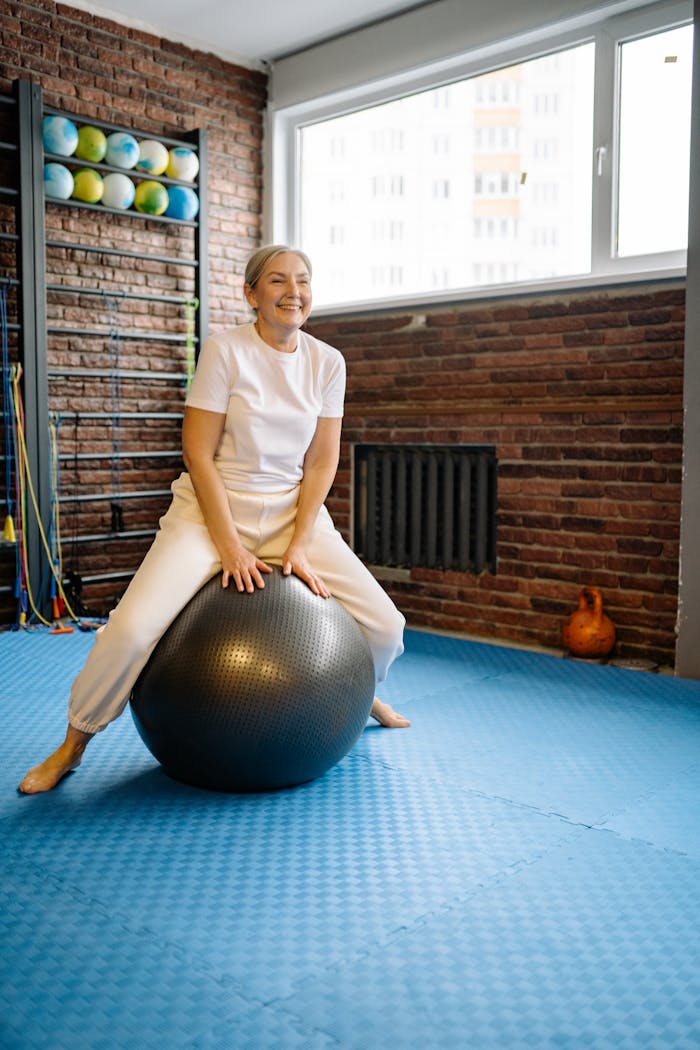 Senior woman enjoying exercise on stability ball in gym setting, promoting active lifestyle.